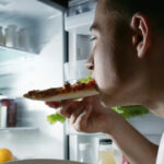 Person eating in front of fridge